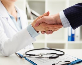 Woman doctor shaking hand with businessman in the office