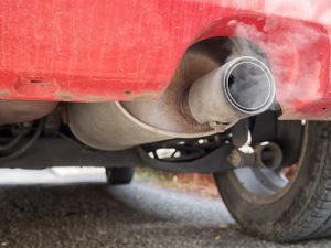 Diesel exhaust, old red car. Detail. With smoke.