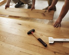 Two men laying finished parquet flooring, close-up