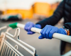 Close-up view of hands in rubber gloves pushing shopping carts.